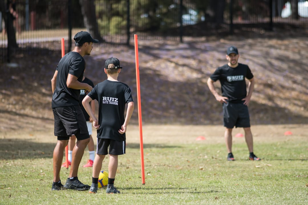 Entrenador guiando una sesion de trabajo con jugador en campo